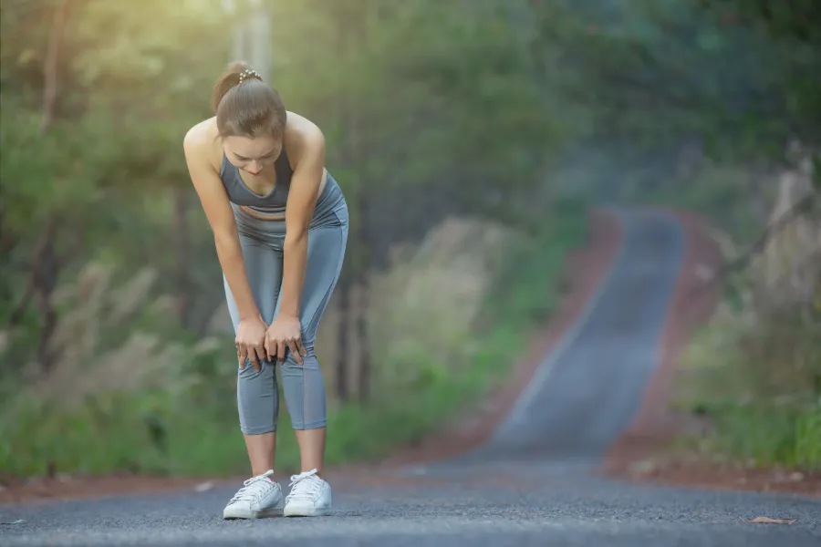 a woman runner holding her knee in pain